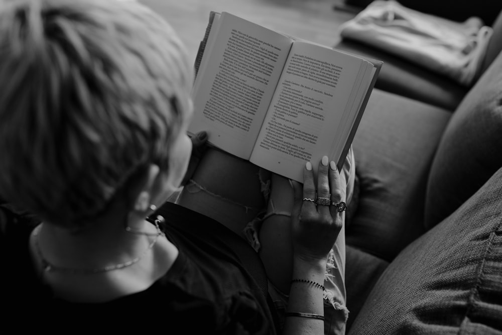 a woman sitting on a couch reading a book