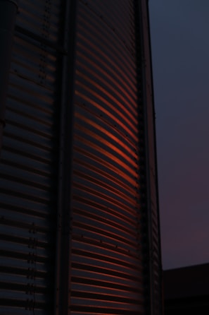 Detailed view of a hairline-finished steel surface reflecting neon orange accents in an industrial setting.