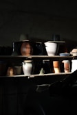 A display of assorted ceramic pots in earthy tones arranged on wooden shelves.