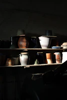 Brightly glazed ceramic mugs and vases displayed together with natural light highlighting their textures