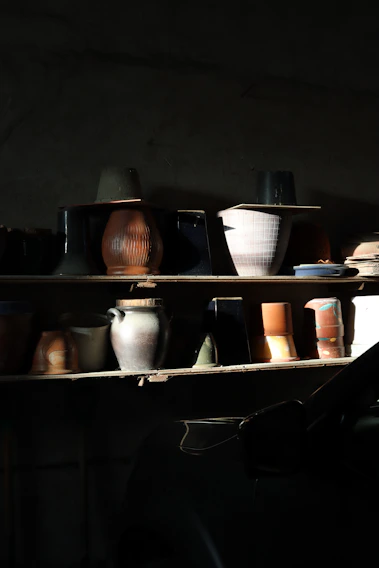 A vibrant display of colorful mid-century ceramic vases arranged on a sunlit wooden shelf.