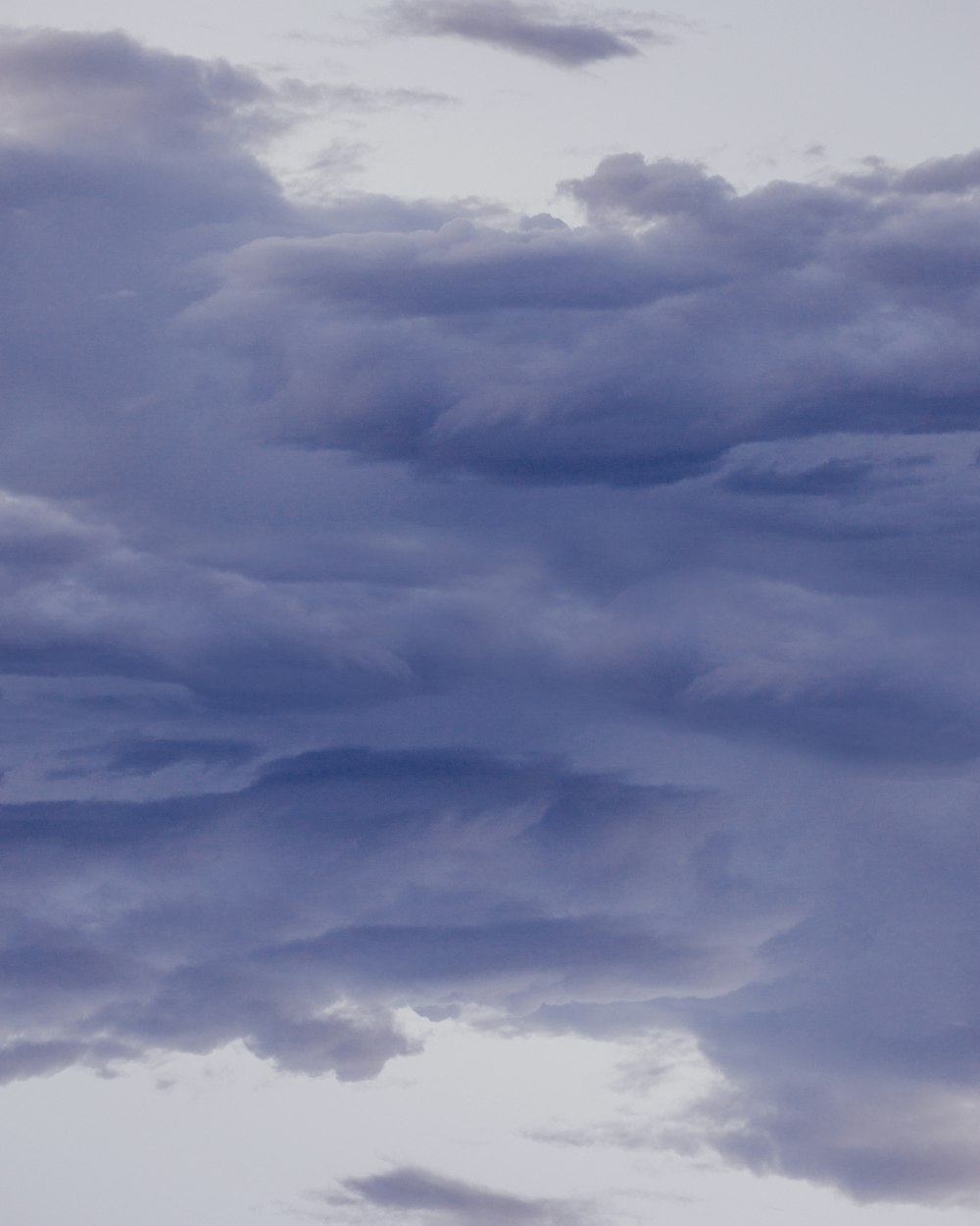 a plane flying through a cloudy blue sky