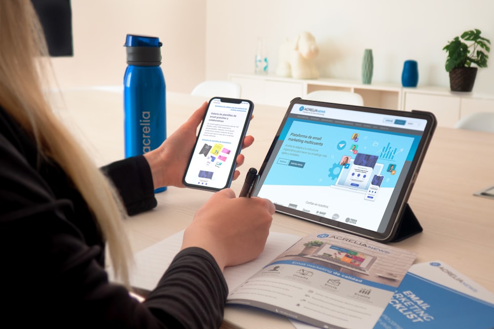 a woman sitting at a table using a tablet