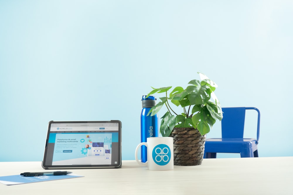 a laptop computer sitting on top of a table next to a potted plant