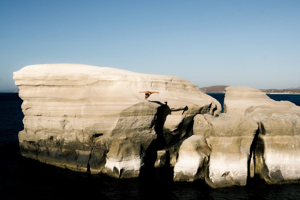 a person standing on top of a large rock near the ocean