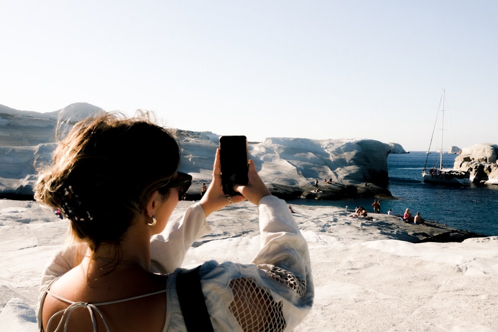 a woman taking a picture of a boat in the water