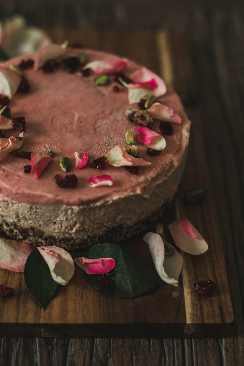 a cake with pink frosting and flowers on a cutting board