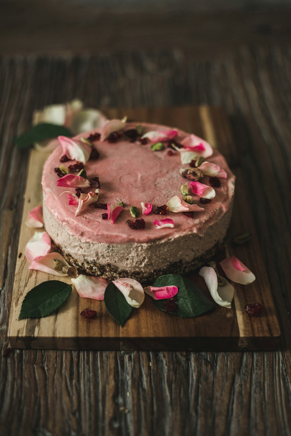 a cake with pink frosting and flowers on a wooden board