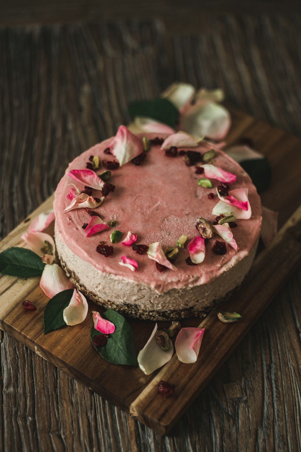 a cake with pink frosting and flowers on a wooden board