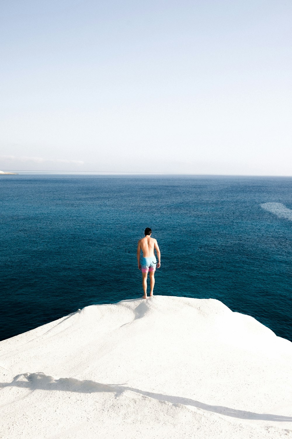 a man standing on top of a snow covered hill next to the ocean