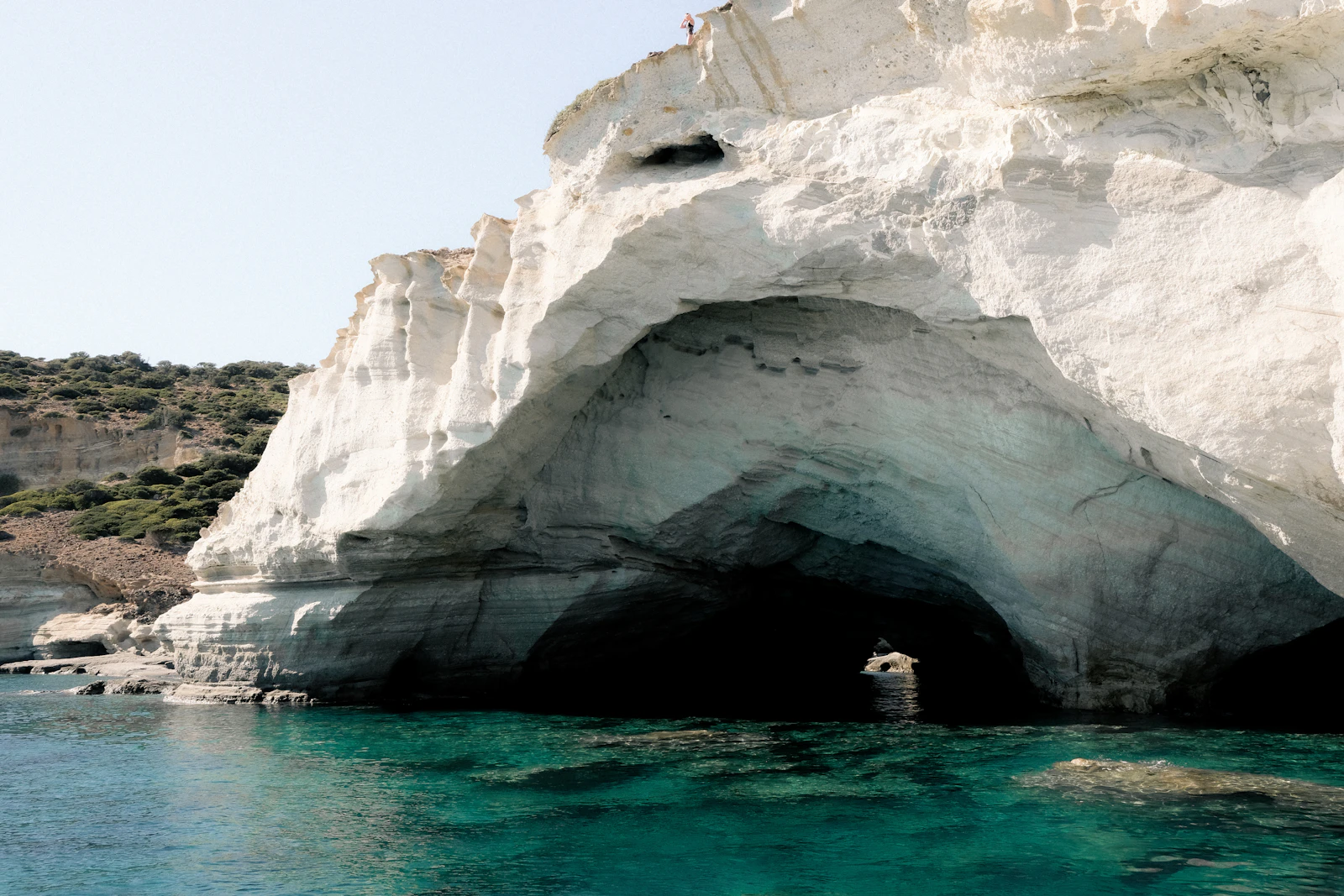 A white rock arch over turquoise water on the Milos coast