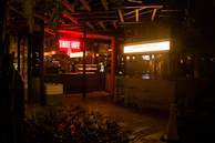 Front storefront of chillibees restaurant at dusk, glowing warmly with emerald and gold signage.