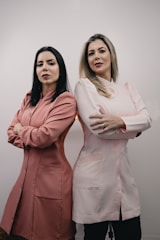 two women standing next to each other with their arms crossed