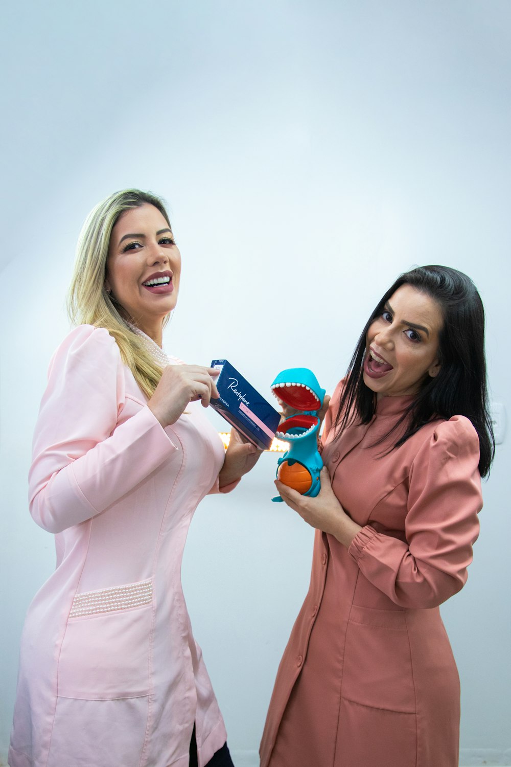 two women standing next to each other holding a toothbrush