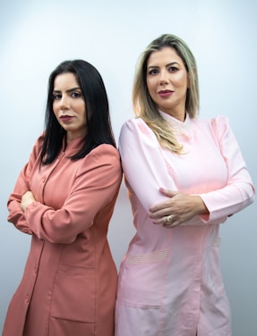 two women standing next to each other with their arms crossed