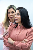 two women standing next to each other with their arms crossed