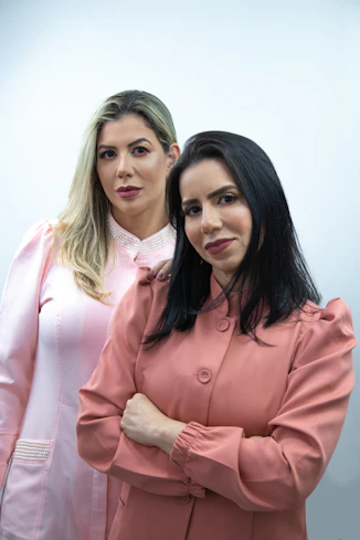 two women standing next to each other with their arms crossed
