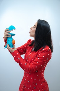 a woman in a red dress holding a blue toy