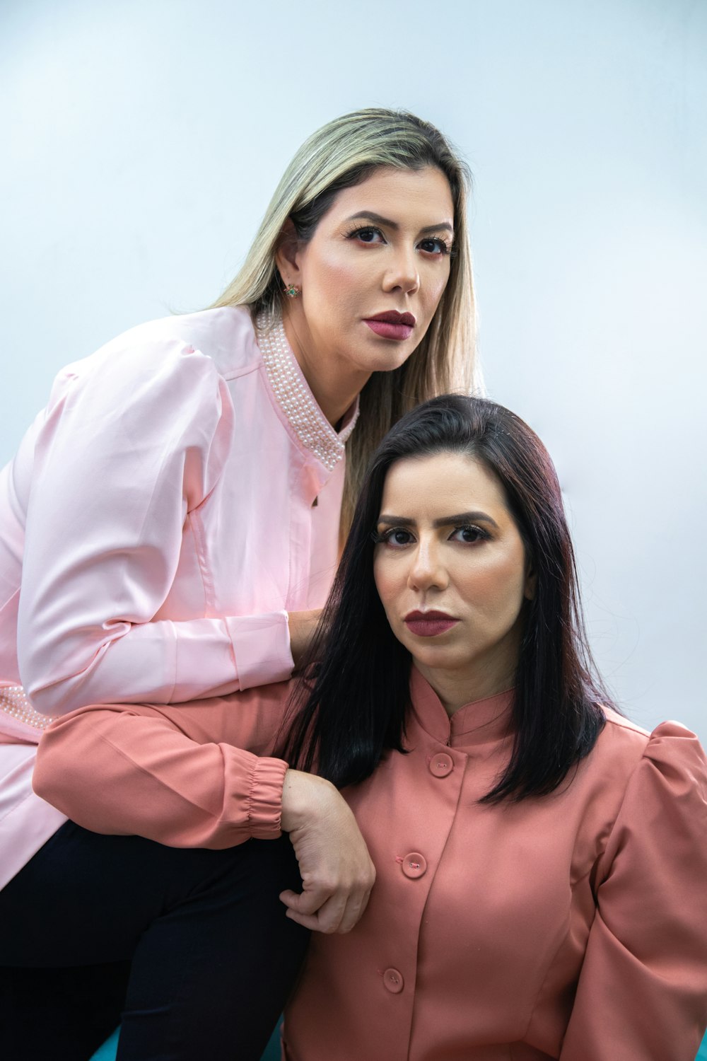 a woman sitting next to a woman in a pink shirt