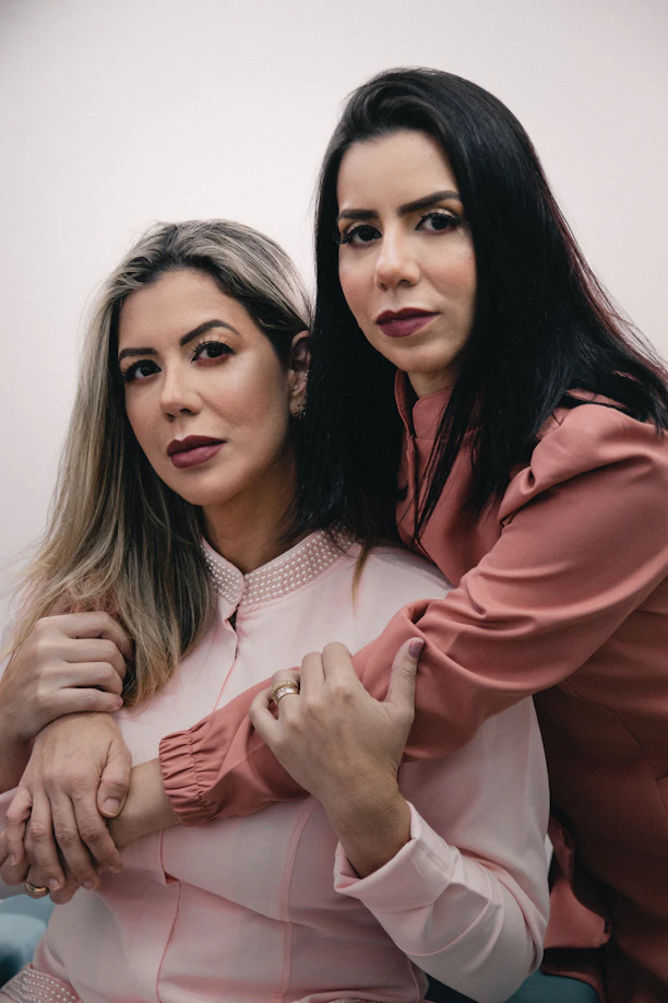 two women standing next to each other in front of a mirror
