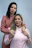 a woman standing next to a woman who is straightening her hair