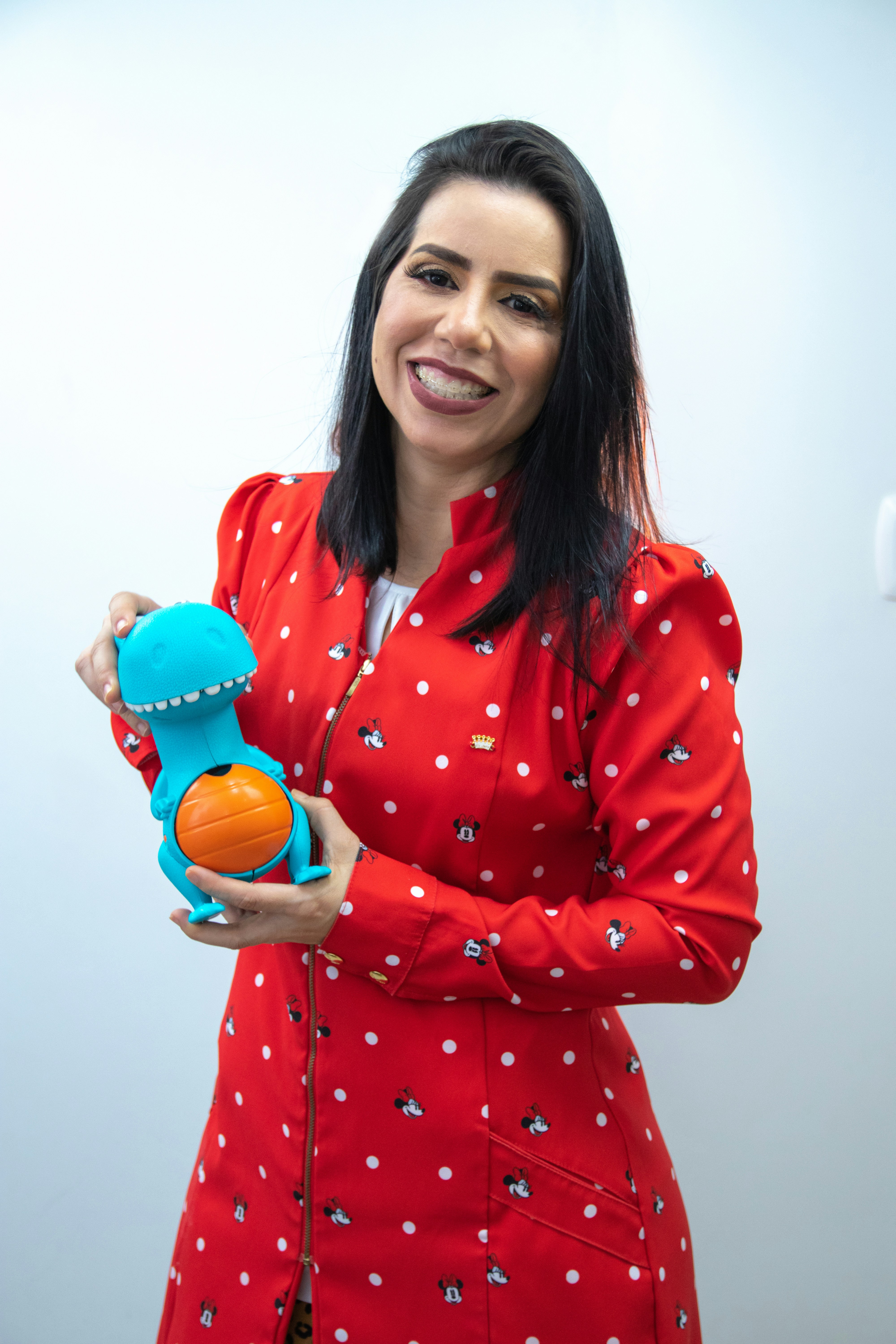 a woman in a red jacket holding a blue toy