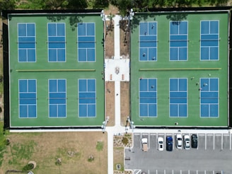 an aerial view of a tennis court and parking lot