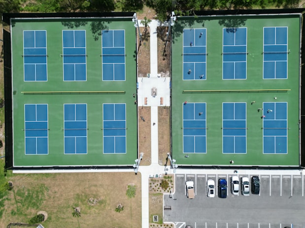 an aerial view of a tennis court and parking lot