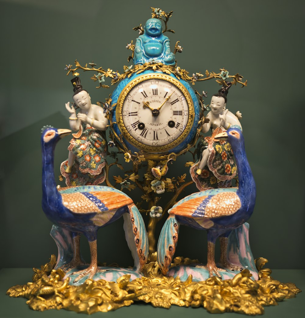 a clock with two peacocks sitting on top of it