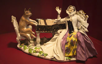 a figurine of a woman playing a piano with a cat