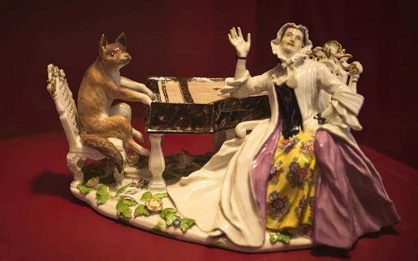 a figurine of a woman playing a piano with a cat