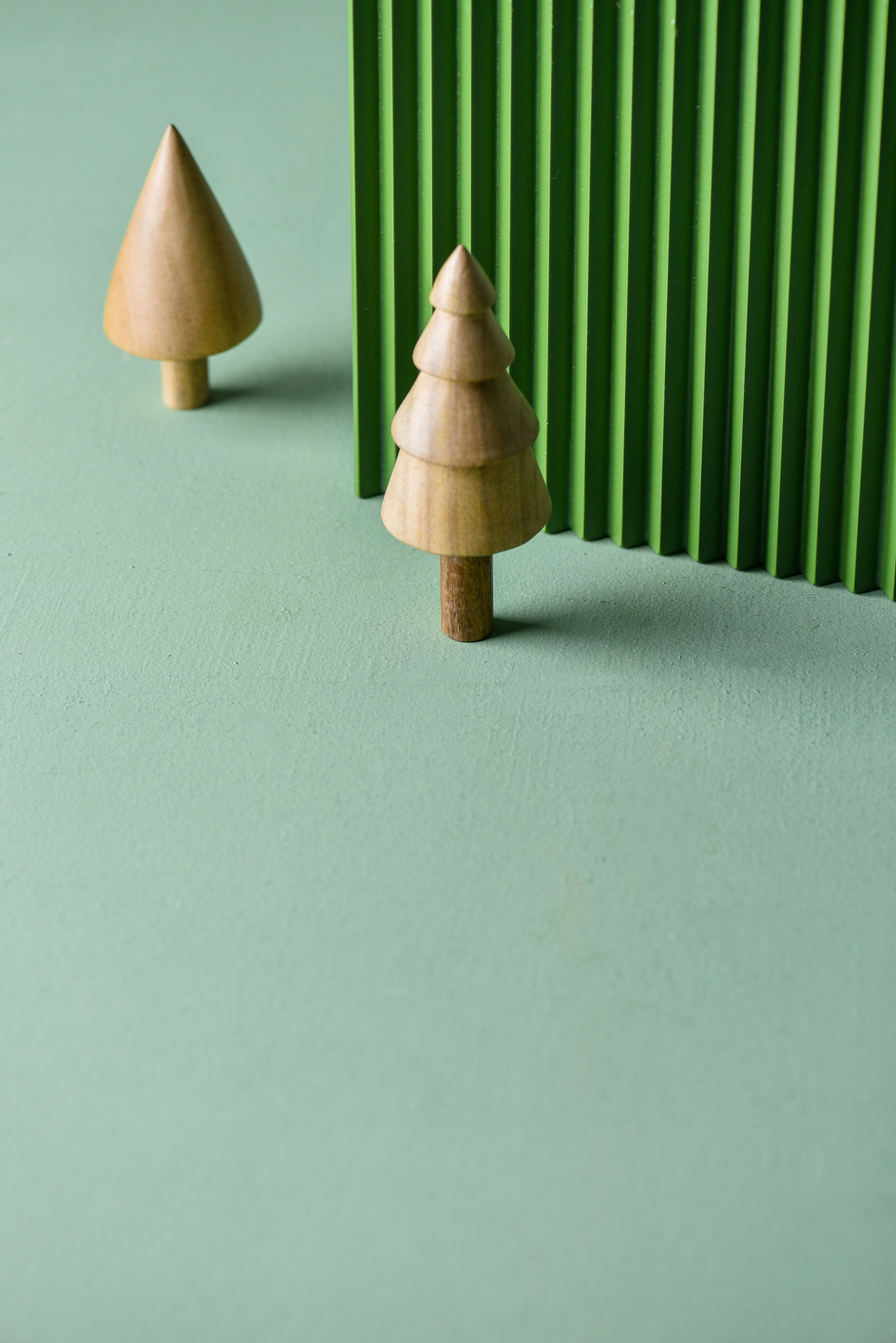 a small wooden christmas tree next to a green wall