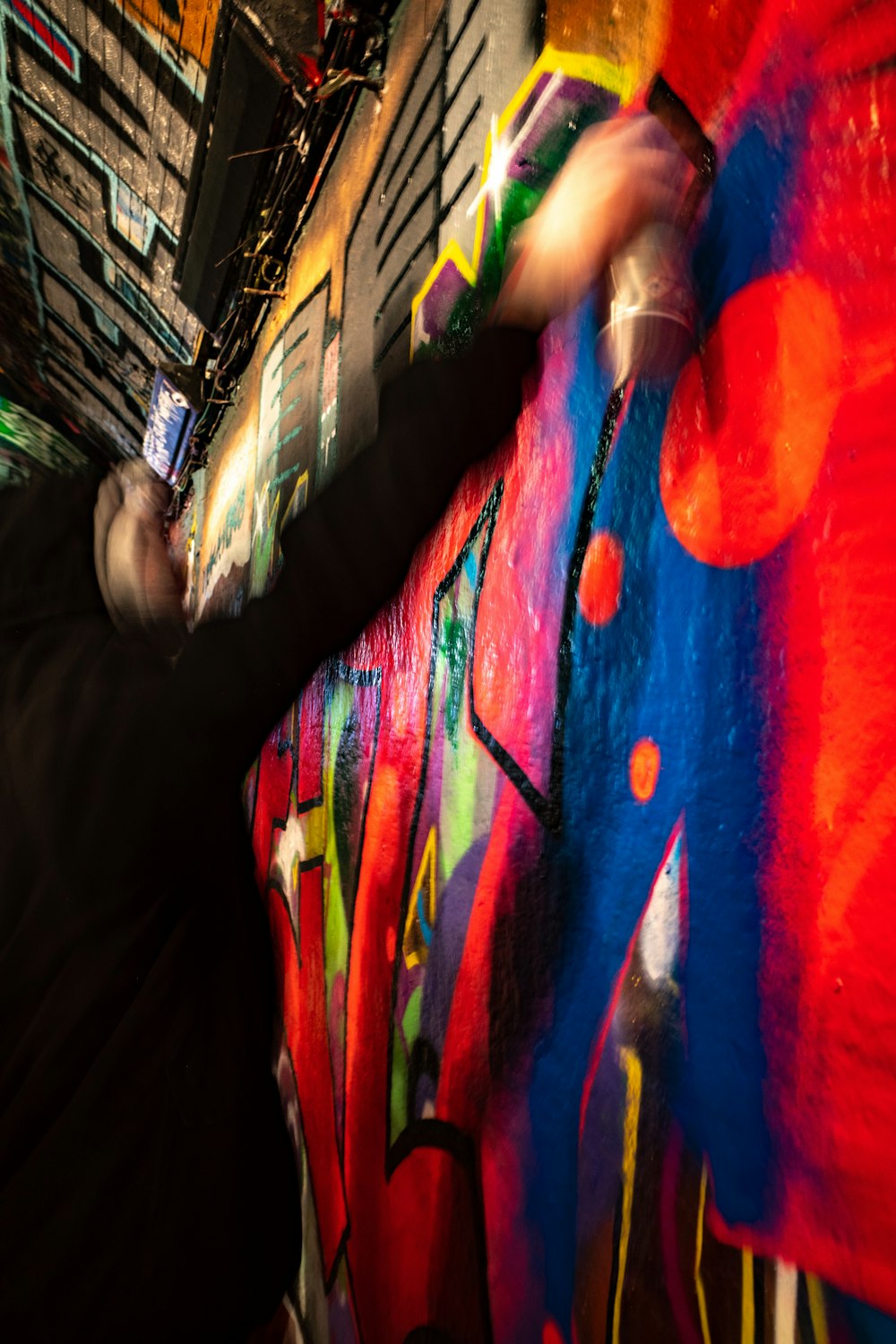 a man is painting a colorful wall with spray paint
