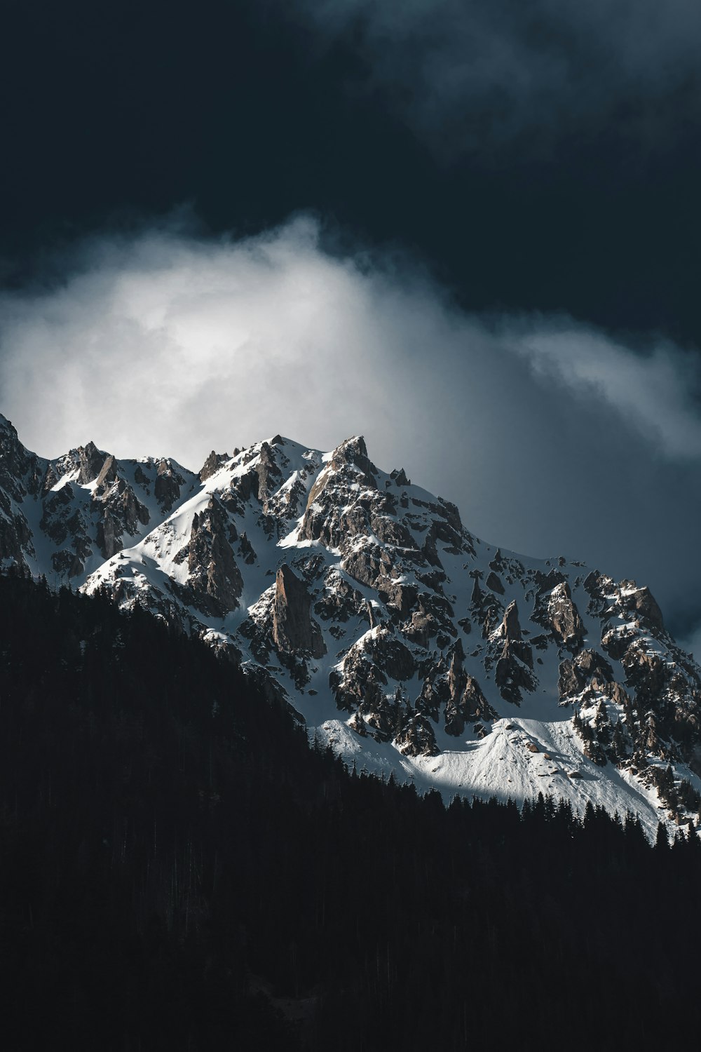 a mountain covered in snow under a cloudy sky