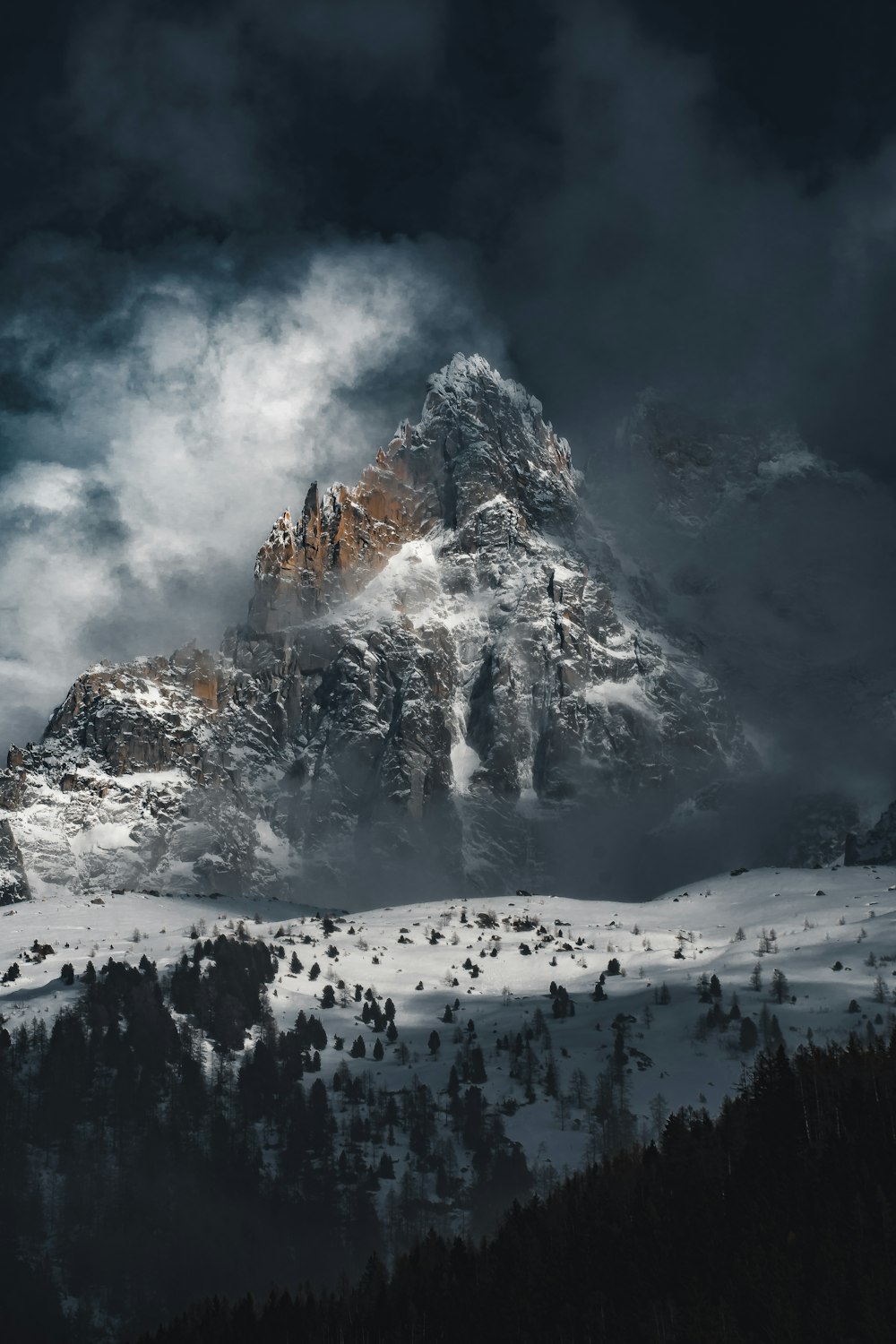 a mountain covered in snow under a cloudy sky