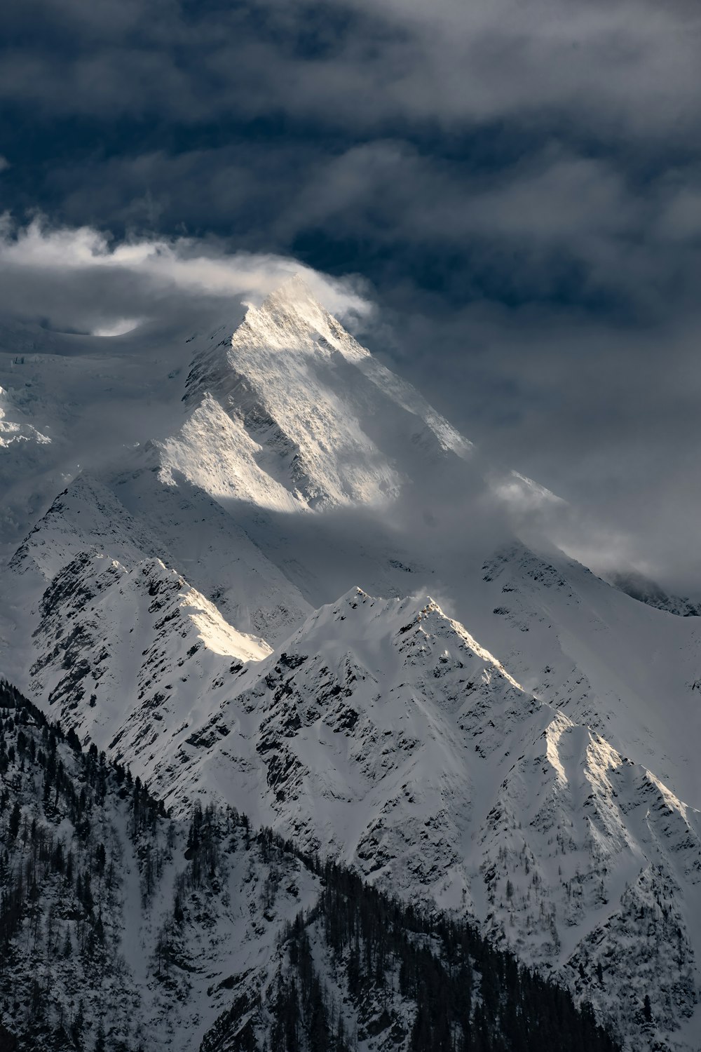 a mountain covered in snow under a cloudy sky