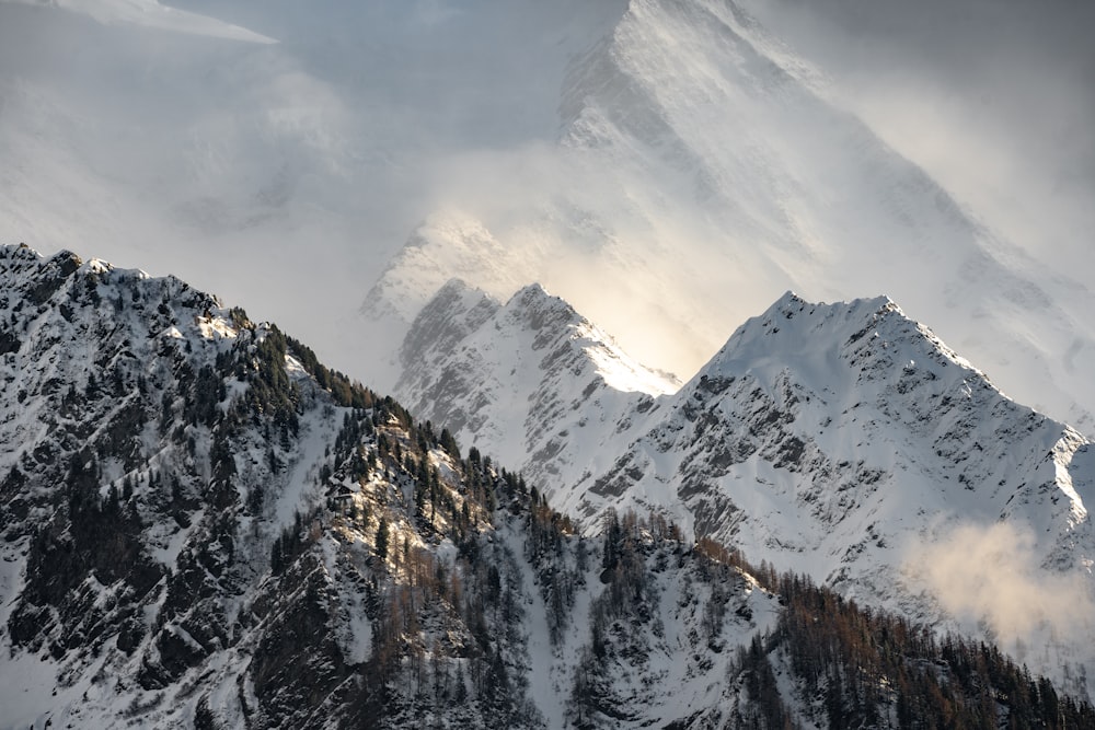 a mountain covered in snow and clouds under a cloudy sky