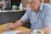 a man sitting at a table writing on a piece of paper