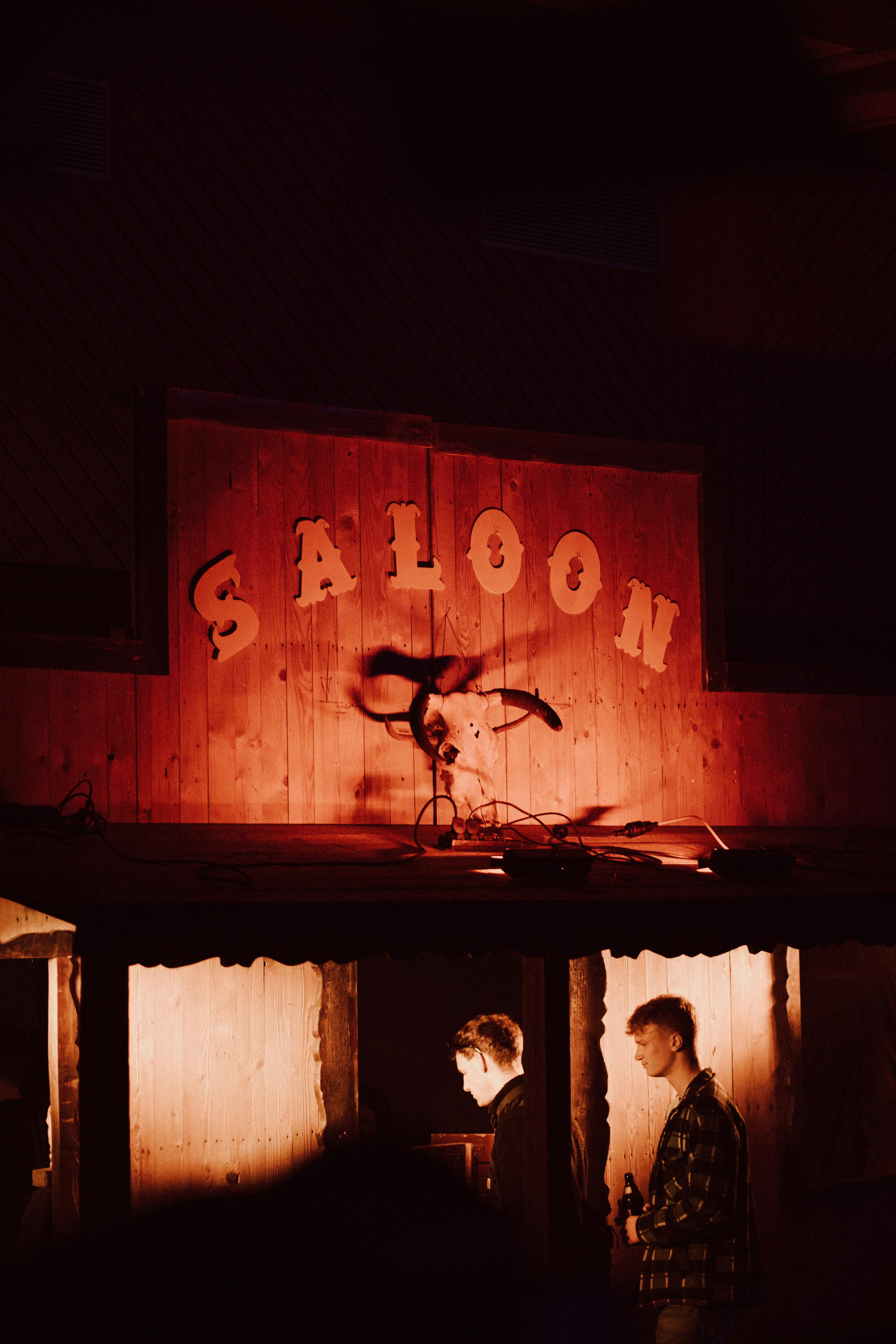 two people standing outside of a saloon at night