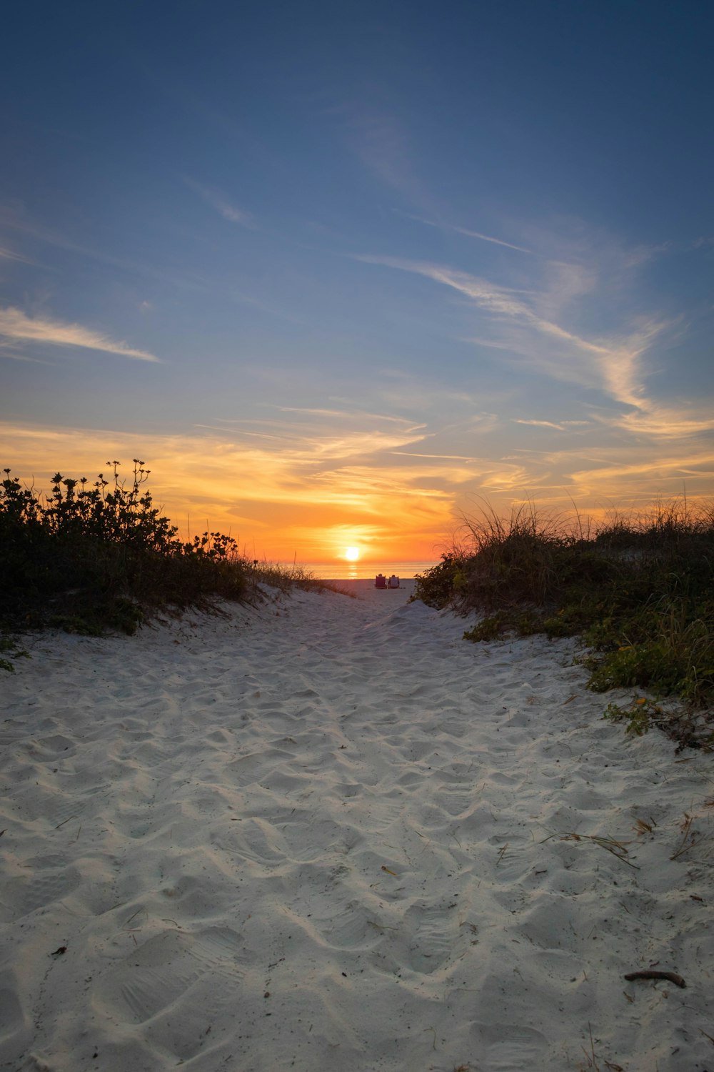 the sun is setting over a sandy beach