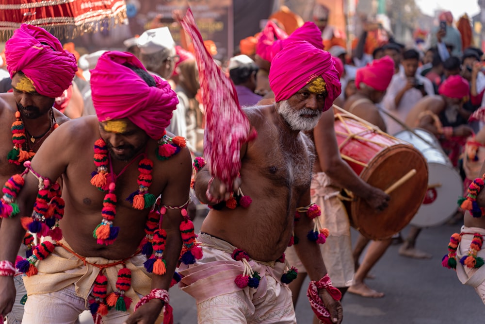 분홍색 터번을 쓴 한 무리의 남자들이 거리를 걷고 있다