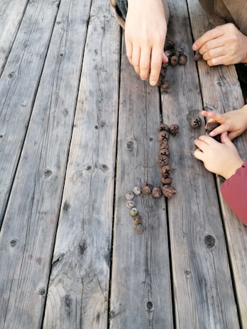 Hands gently arranging symbolic objects on a wooden table during a systemic constellation session