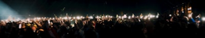 Fans holding up glowing signs and phones at a nighttime Tampa rap show.