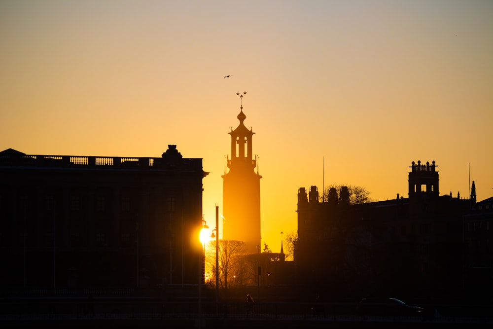 a large clock tower towering over a city at sunset