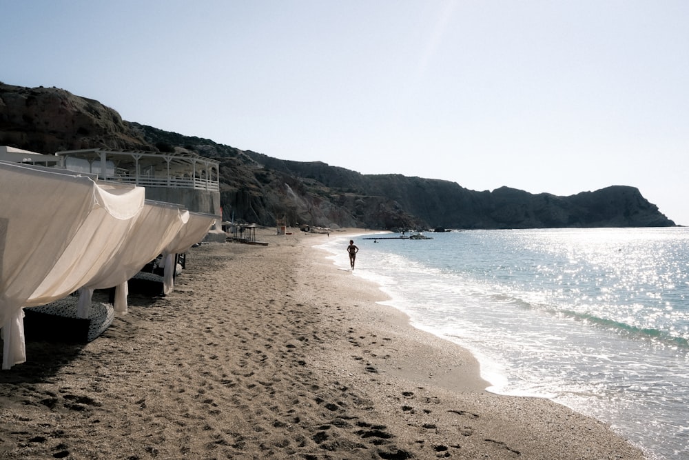 a person walking on a beach next to boats