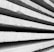 Rough concrete slabs are stacked closely on top of each other, showcasing their textured surfaces and industrial appearance. The perspective highlights the lines and shadows formed between the slabs.