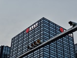 A tall, modern office building with a grid-like facade of windows is prominently visible. The logo and name 'China Merchants Bank' are displayed in white and red on the top of the building. In the foreground, there is a traffic light hanging on a metal pole.