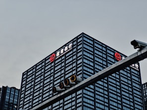 A tall, modern office building with a grid-like facade of windows is prominently visible. The logo and name 'China Merchants Bank' are displayed in white and red on the top of the building. In the foreground, there is a traffic light hanging on a metal pole.