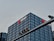A tall, modern office building with a grid-like facade of windows is prominently visible. The logo and name 'China Merchants Bank' are displayed in white and red on the top of the building. In the foreground, there is a traffic light hanging on a metal pole.