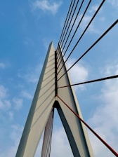A panoramic view of a massive cable-stayed bridge under construction against a clear sky.